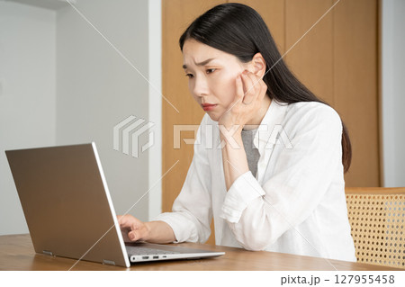パソコンの画面を見て悩む女性 127955458