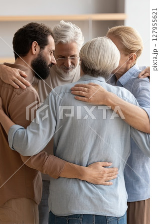 Participants uplift each other with encouraging and loving hugs. Group therapy and support: middle aged men and women hug, supporting each other during psychological practice. 127955621