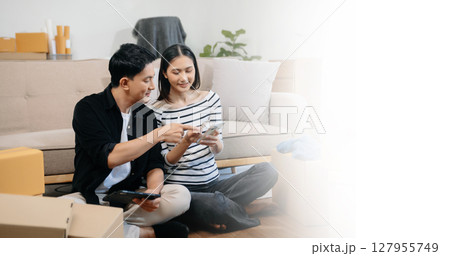 Asian young attractive couple man and woman use tablet and smartphone online shopping furniture decorate house with carton package move in new house. Asian young attractive couple man and woman use tablet and smartphone online shopping furniture decorate house with carton package move in new house. 127955749
