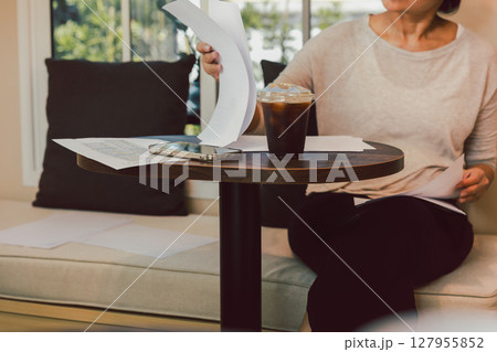 Select focus on Iced black coffee with woman reading documents in cafe. Select focus on Iced black coffee with woman reading documents in cafe. 127955852