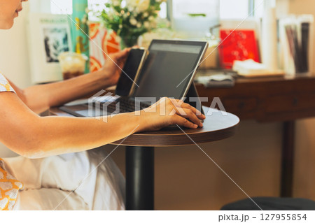 Woman hand holding computer mouse working on laptopin cafe. 127955854