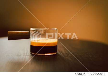 Espresso coffee in a glass cup on wooden table. Espresso coffee in a glass cup on wooden table. 127955855