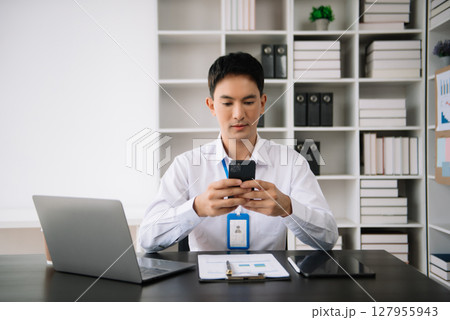 Confident Asian man with a smile standing holding notepad and tablet at the modern office. Confident Asian man with a smile standing holding notepad and tablet at the modern office. 127955943