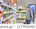 Man Carefully Considers Grocery Shopping Options Today 127956060