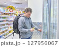Man Carefully Selects Beverage From Cooler Display 127956067