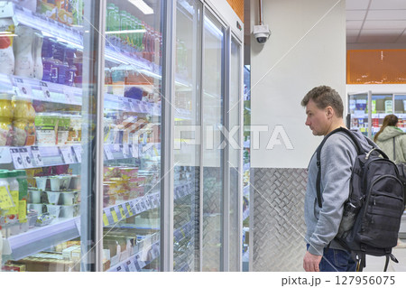 Man Browses Refrigerated Goods At Grocery Store 127956075