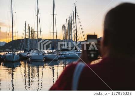Person Capturing Sailboats at Sunset in Harbor Person Capturing Sailboats at Sunset in Harbor 127956328