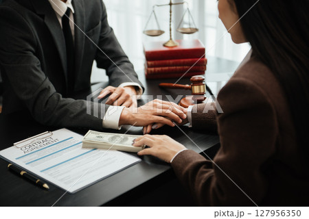 Judge gavel with scales of justice, Business and lawyer or counselor consulting and discussing contract papers with laptop and tablet at law firm Judge gavel with scales of justice, Business and lawyer or counselor consulting and discussing contract papers with laptop and tablet at law firm 127956350