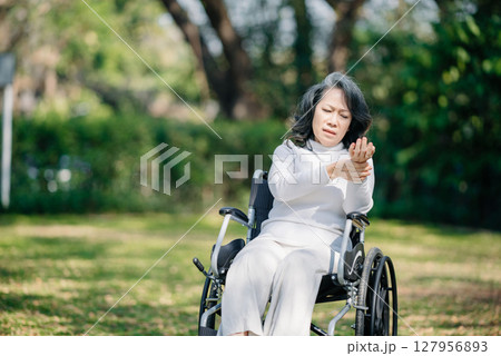 Asian old woman sitting on a wheelchair outdoors in the garden There is pain in the heart 127956893