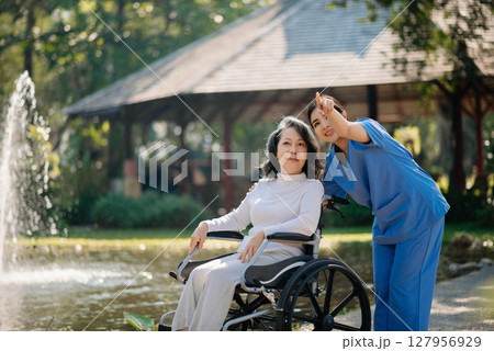 Asian young caregiver nurse support senior older male walking outdoors. Specialis doctor help and take care of elderly mature. 127956929