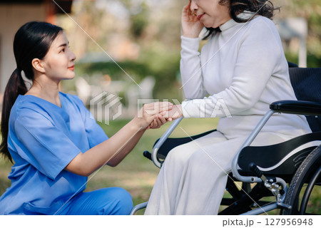 Asian young caregiver nurse support senior older male walking outdoors. Specialis doctor help and take care of elderly mature. Asian young caregiver nurse support senior older male walking outdoors. Specialis doctor help and take care of elderly mature. 127956948