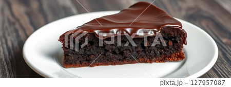 Delicious chocolate cake slice served on a white plate with a wooden background 127957087