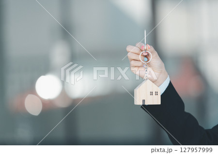 Woman hand hold key buy home model business concept involves sell financial management investment bank loan ownership income economy finance investments purchasing apartment blur background estate 127957999