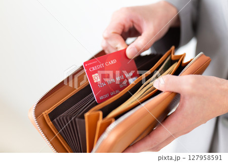 財布からクレジットカードを出すスーツ姿のミドル女性 127958591