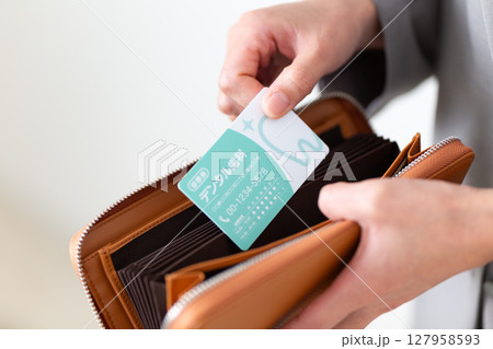 財布から歯医者の診察券を出すスーツ姿のミドル女性 127958593