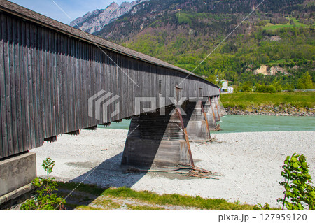 Covered wooden old bridge (Alte Rheinbrucke) the across the river Rhine between Vaduz, Liechtenstein and Sevelen, Switzerland 127959120