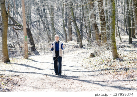 Young woman nordic walking in forest during winter sunny day 127959374