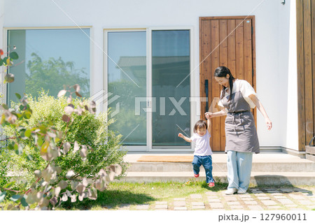 庭で手を繋いで歩く親子 127960011