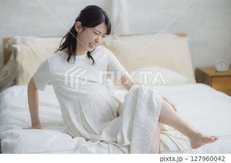 寝室でベッドに座る足が攣った女性 127960042