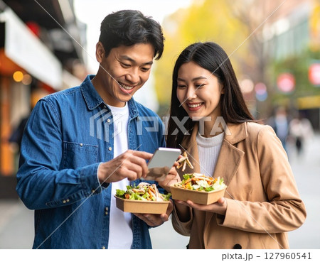 スマホを見ながらPFCバランスが整ったサラダチキンを食べる男性と女性 127960541