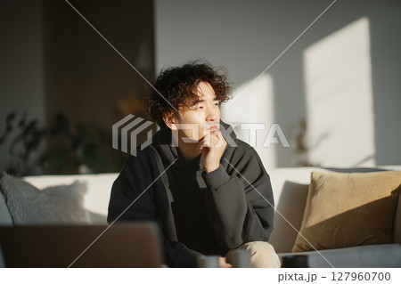 自宅で思索にふける若いアジア人男性。リラックスした日常のひとコマ 127960700