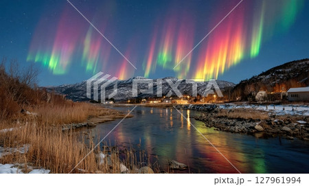 Norway's aurora borealis paints the night sky Colors reflect in the river amidst a snow-kissed, wintery landscape 127961994