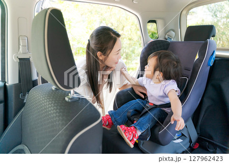 子供をチャイルドシートに座らせるママ 子供をチャイルドシートに座らせるママ 127962423
