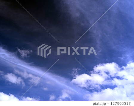 Close up of atmospheric blue black sky with whispy white clouds 127963517