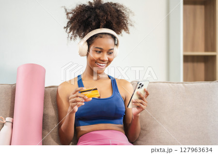 Fit woman enjoys fresh fruit and scrolls social media after yoga. Healthy lifestyle, fitness, wellness. 127963634