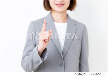 人差し指を立てるスーツ姿のミドル女性 127965408