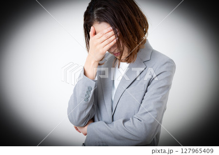 頭を抱えて苦しむスーツ姿のミドル女性 127965409