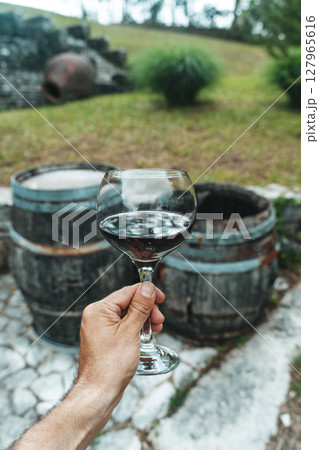 Red Wine Glass in Hand with Stone Cellar Background in France or Italy 127965616