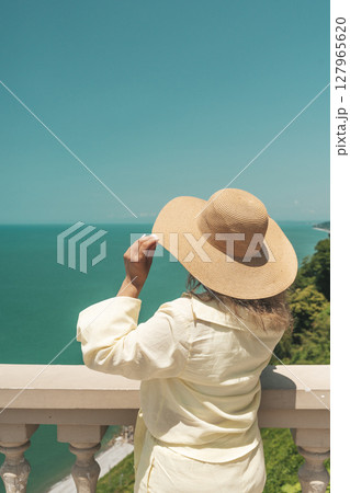 Woman in Summer Hat Looking at Sea Horizon from Cliff Woman in Summer Hat Looking at Sea Horizon from Cliff 127965620