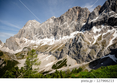 Dramatic Dachstein mountain peaks with lush green valley and clouds in Austria Dramatic Dachstein mountain peaks with lush green valley and clouds in Austria 127966213