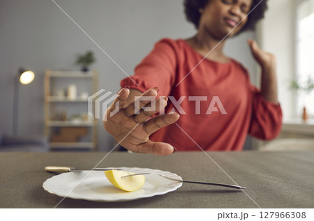 Annoyed hungry young woman hates dieting and pushes plate with piece of apple away 127966308