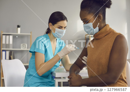 Female medical worker making vaccination against covid-19 for black woman 127966587