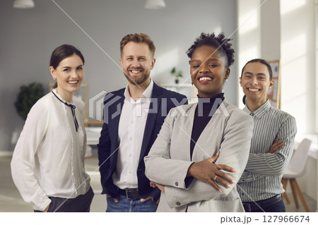 Portrait of a positive young multiracial team posing in the office looking at the camera. 127966674