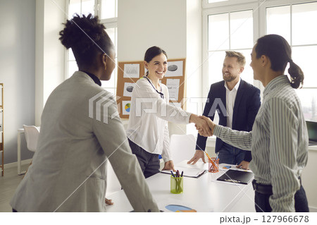 Smiling young people greeting each other before negotiation at the company office 127966678