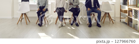Cropped image of the legs of various people sitting on chairs and waiting their turn. Cropped image of the legs of various people sitting on chairs and waiting their turn. 127966760