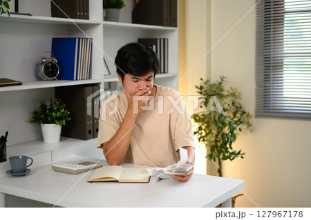 Man checks bills and expenses, feeling overwhelmed by home financial responsibilities 127967178