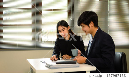 Businesspeople examining paperwork and negotiating details during a formal contract discussion 127967188