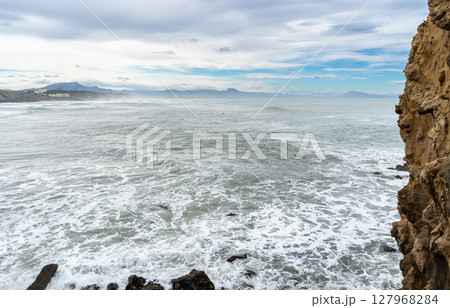 Waves crash against the rocky French Atlantic coast near Biarritz with visible cliff formations 127968284