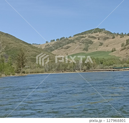 Picturesque Landscape Featuring a Tranquil River Flowing Through Rolling Hills and Lush Greenery 127968801