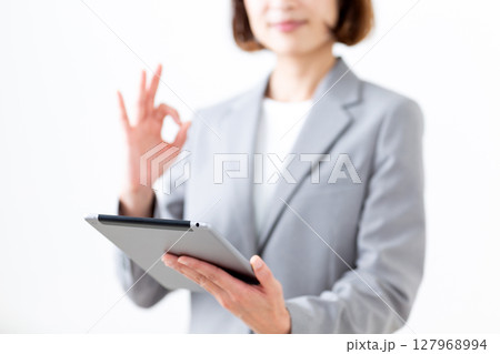 タブレットを持って丸サインをするグレーのスーツ姿のミドル女性 127968994
