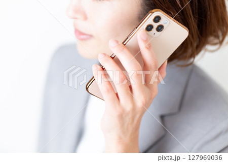 スマホで通話するグレーのスーツ姿のミドル女性 127969036