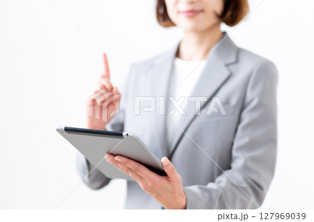 タブレットを持って人差し指を立てるグレーのスーツ姿のミドル女性 タブレットを持って人差し指を立てるグレーのスーツ姿のミドル女性 127969039