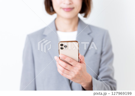 スマホを持つグレーのスーツ姿のミドル女性 127969199