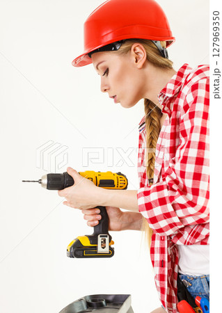 Woman using drill on ladder Woman using drill on ladder 127969350