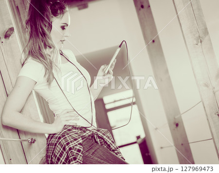 Woman with headphones choose music on smartphone. Woman with headphones choose music on smartphone. 127969473