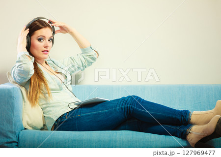 Woman with tablet headphones sitting on couch Woman with tablet headphones sitting on couch 127969477